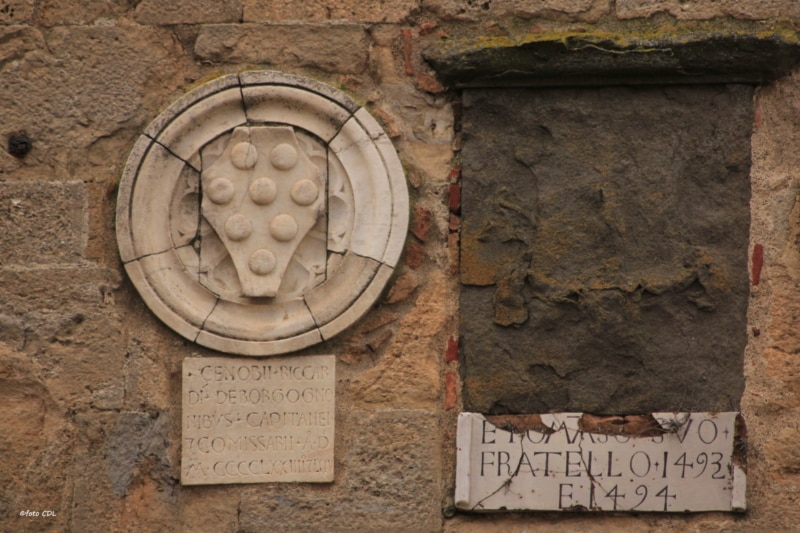 Volterra: Palazzo dei Priori. Lo stemma di Cosimo il Vecchio con 8 palle disposte in modo diverso all'interno dello scudo. L'epoca di Cosimo il Vecchio è confermata dalle iscrizioni limitrofe: una del 1493-94 e l'altra del 1473-74